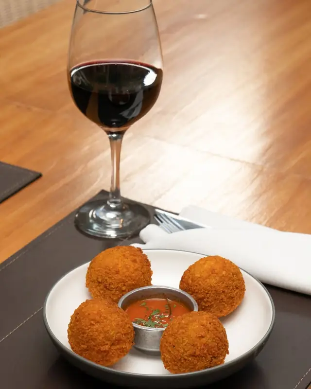 Croquetas de surubí de Goya con copa de vino en Charqui, Palermo