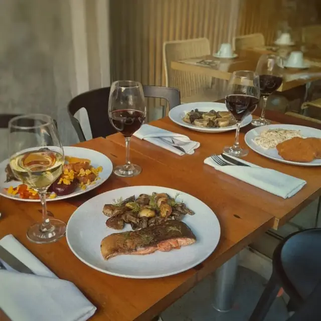 Mesa con trucha patagónica y copas de vino en Charqui, Palermo